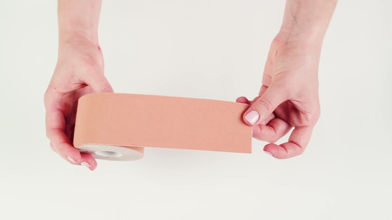 Kinesiology medical taping, doctor Physical therapist applying elastic surgical tape to patient body, treating injured knee young athlete.Post traumatic rehabilitation, sport physical therapy recovery