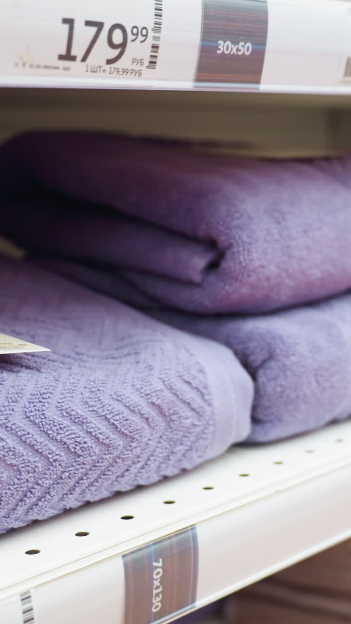vista de toallas púrpuras bien dispuestas en los estantes de las tiendas. capturado con una cámara de mano, este video muestra la exhibición organizada y la variedad de toallas en un entorno minorista