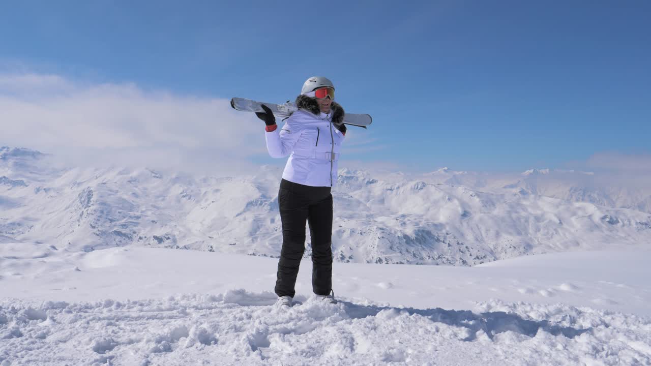 la mujer esquiadora se para en la ladera de la montaña, levanta el esquí y las ondas 4k