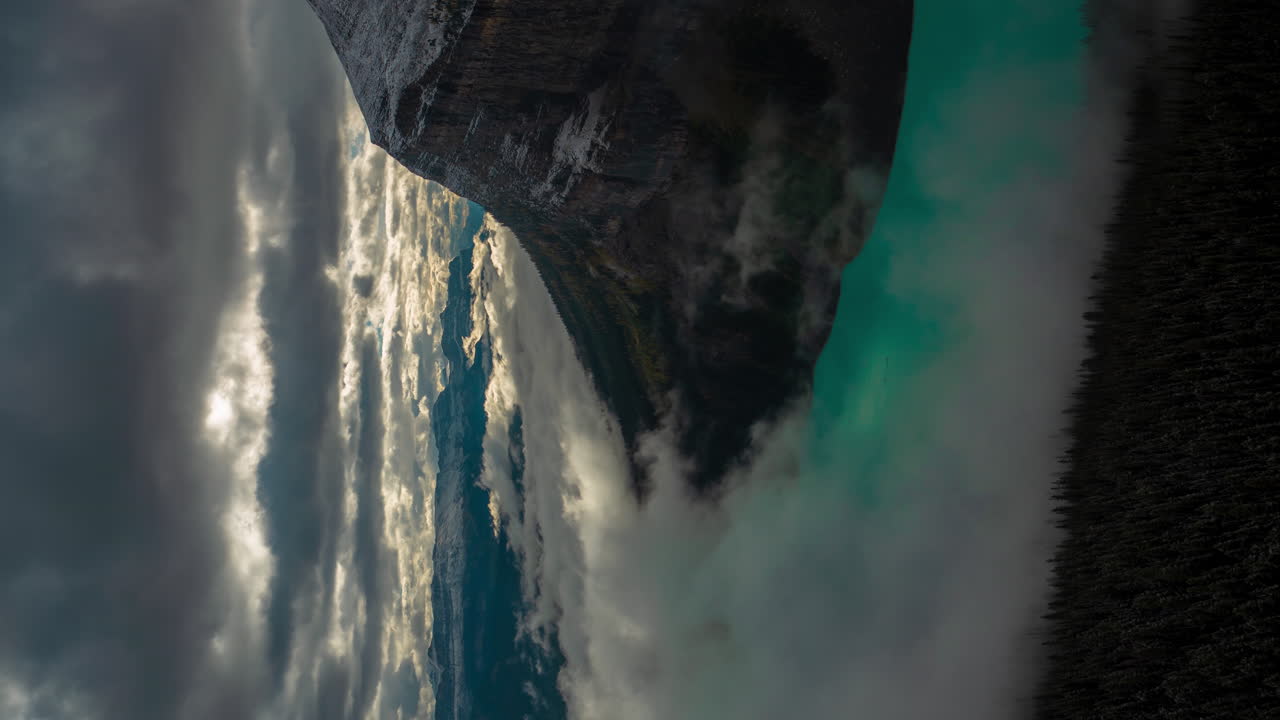 lapso de tiempo vertical de 4k de la magnífica escena de la atmósfera sobre el lago glacial y la montaña cubierta de nieve, inversiones de nubes y niebla, lago louise, parque nacional de banff, alberta, canadá