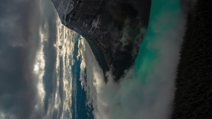 Vertical 4k Time lapse of Magnificent Atmosphere Scene Above Glacial Lake and Snow Capped Mountain, Clouds and Fog Inversions, Lake Louise, Banff National Park Alberta, Canada