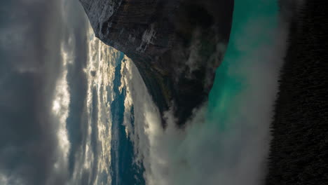 vertical 4k time lapse of magnificent atmosphere scene above glacial lake and snow capped mountain, clouds and fog inversions, lake louise, banff national park alberta, canada