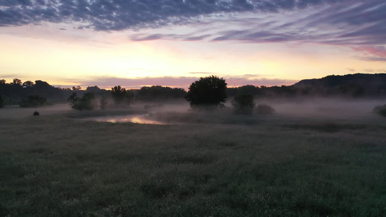 amanecer brumoso sobre un prado y un río