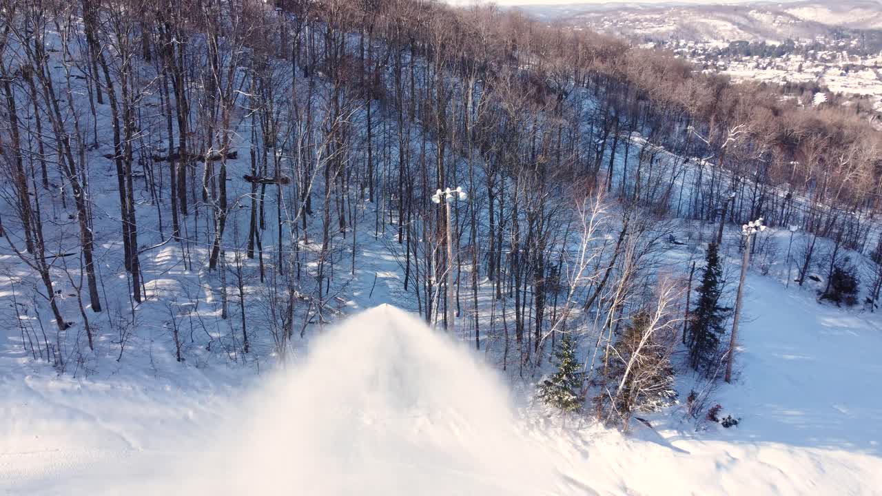 Aerial: snow gun blowing snow on the ski slope in Saint-Sauveur, Quebec, Canada, orbit drone shot