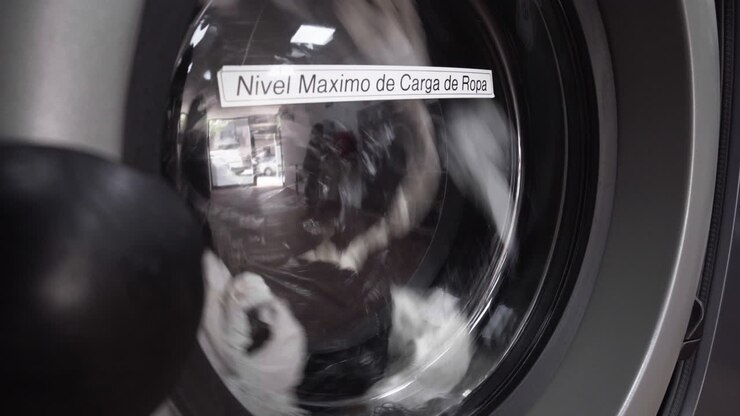 A Front Load Fully Automated Washing Machine Spinning With Clothes Loaded In A Laundry Shop - close up