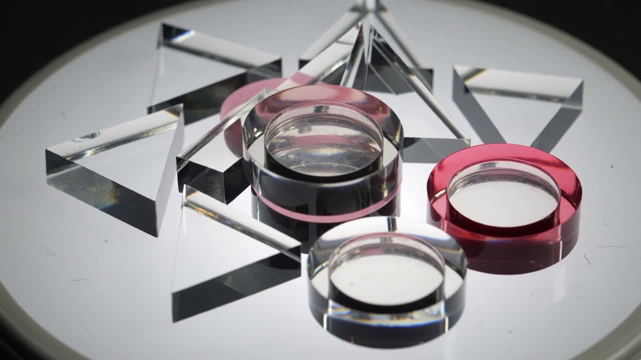 Moving camera, shifting lights showing facets of lens with pink band, discs, ring, prisms on mirror