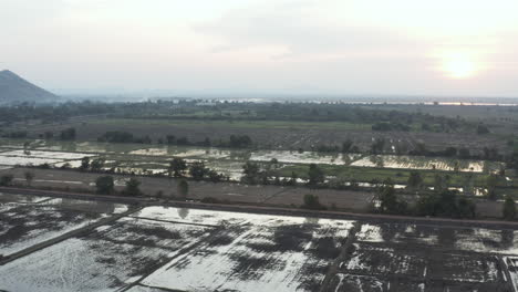 Volando-Sobre-Un-Campo-De-Arroz-Inundado-Con-Una-Montaña-De-Fondo-En-La-Hermosa-Camboya