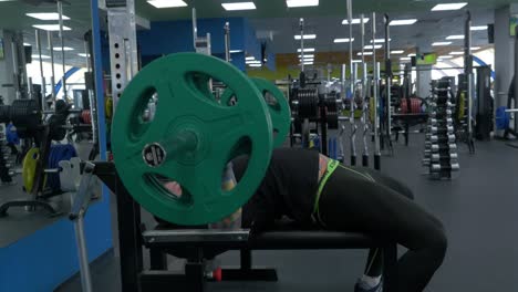 man performing bench press exercise in a gym