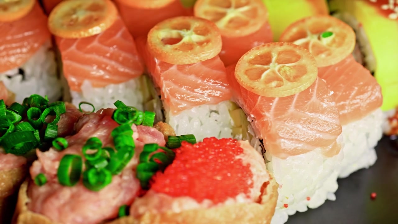 Sushi-Rollen mit Lachs und Avocado, auf einem schwarzen Teller angerichtet, in einem Restaurant bei einem entspannten Essen.
