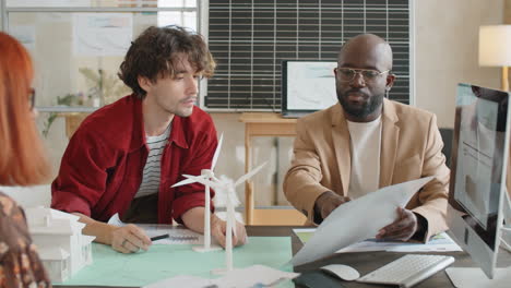 multiethnic engineers discussing project of renewable energy in office