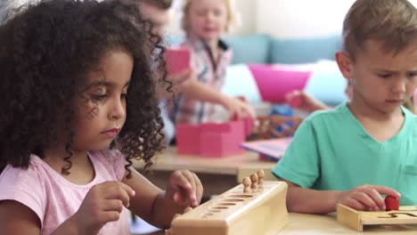 alumnos de montessori trabajando en un escritorio con rompecabezas de forma de madera