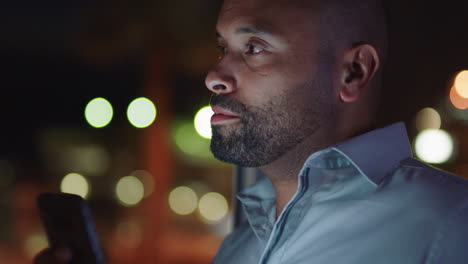 attractive man using smartphone in hotel room at night browsing online checking social media messages enjoying mobile technology