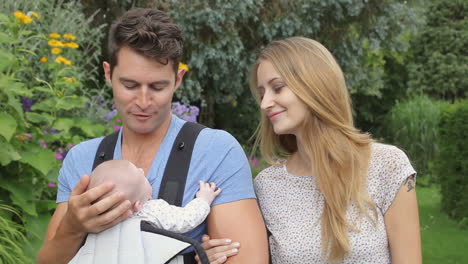 Parents-With-Baby-In-Carrier-On-Walk-In-Garden