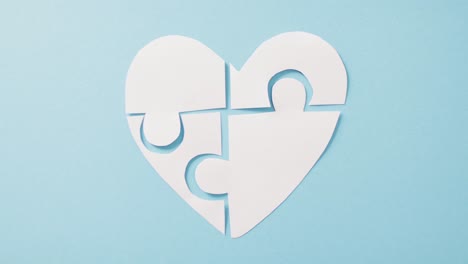 video of white jigsaw puzzle heart on blue background with copy space