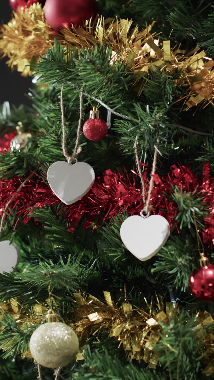 Vertical video of christmas tree with decorations and white hearts with copy space