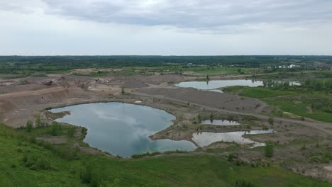 aggregate and gravel pit quarry and surrounding landscape in caledon, ontario. rising drone shot.