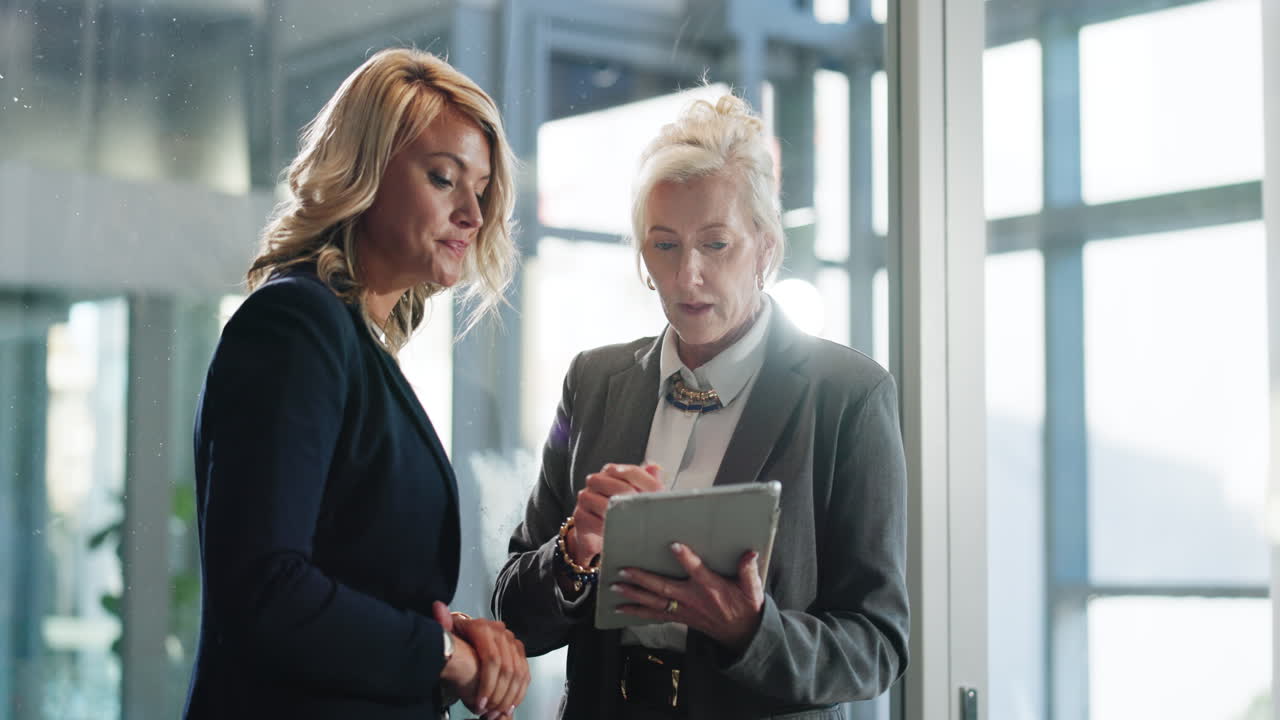 Due donne d'affari che discutono di lavoro su un tablet in un ufficio