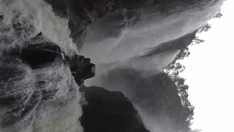 massive hesjedalsfossen waterfall during heavy rain in norway, vertical