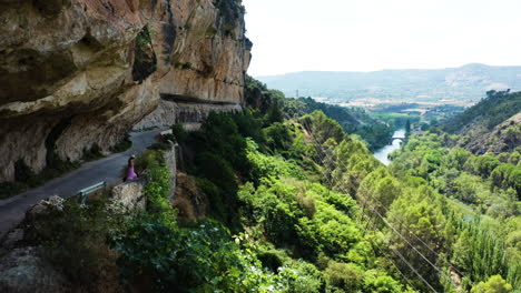 cinematic aerial of woman walking dog along the mirador al puente romano spain.