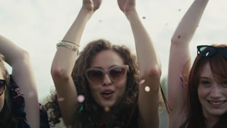 Three-young-caucasian-females-blowing-confetti-towards-the-camera-and-and-later-dance