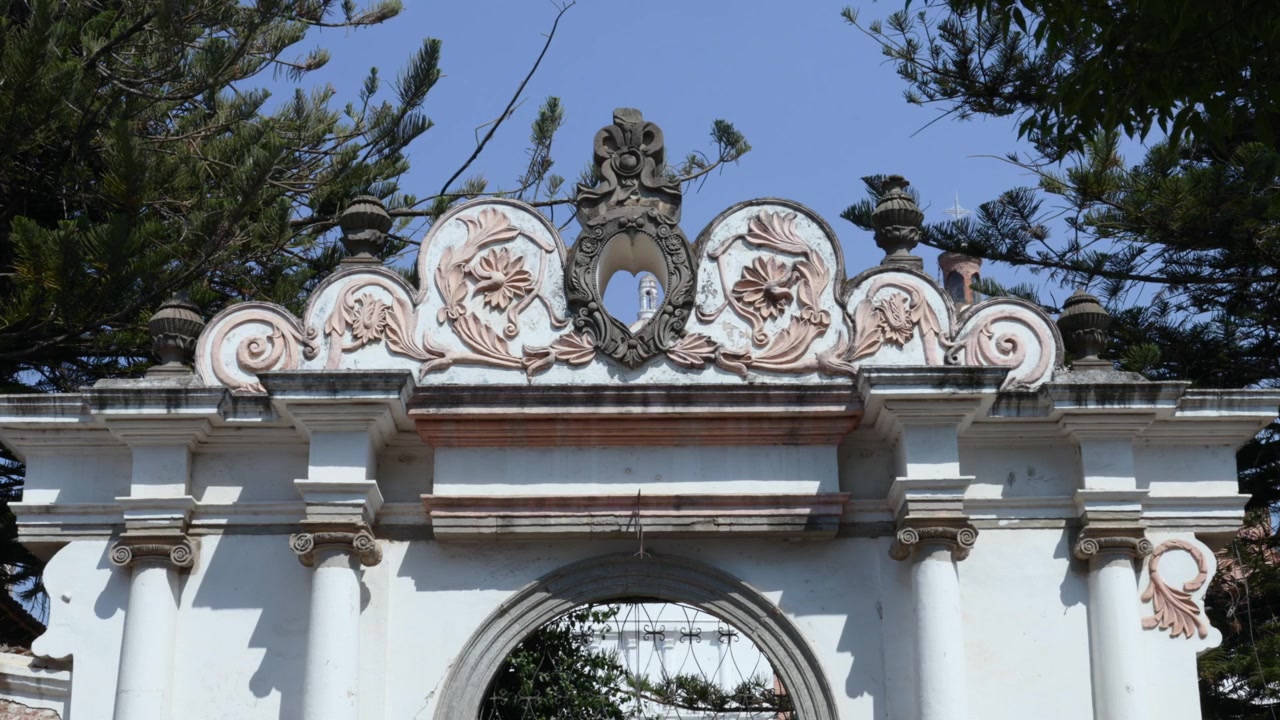 Arco d'ingresso storico ornato con rilievi floreali decorativi e colonne classiche a Tapalpa Pueblo Mágico, Jalisco, Messico. Inquadratura fissa di ambientazione di un punto di riferimento turistico.
