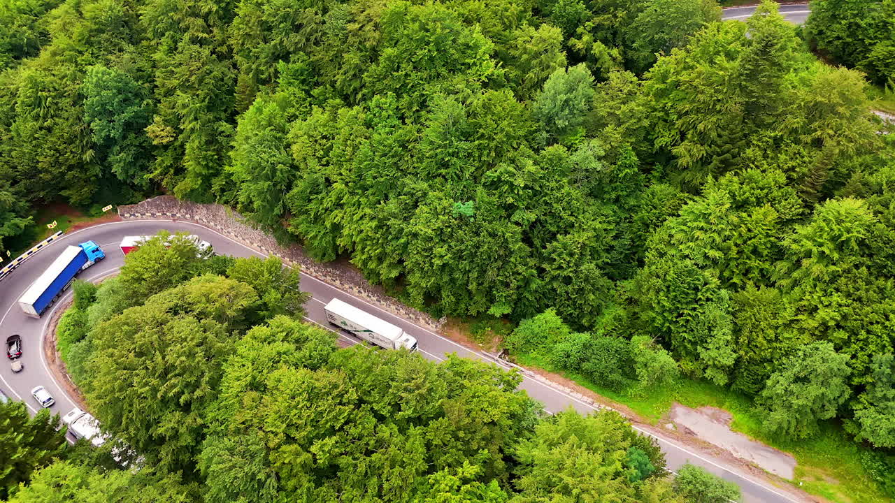 Mountain pass road winding through green forest, Romania. Aerial drone view of a mountain pass road winding through the forested slopes of the Carpathians in Romania