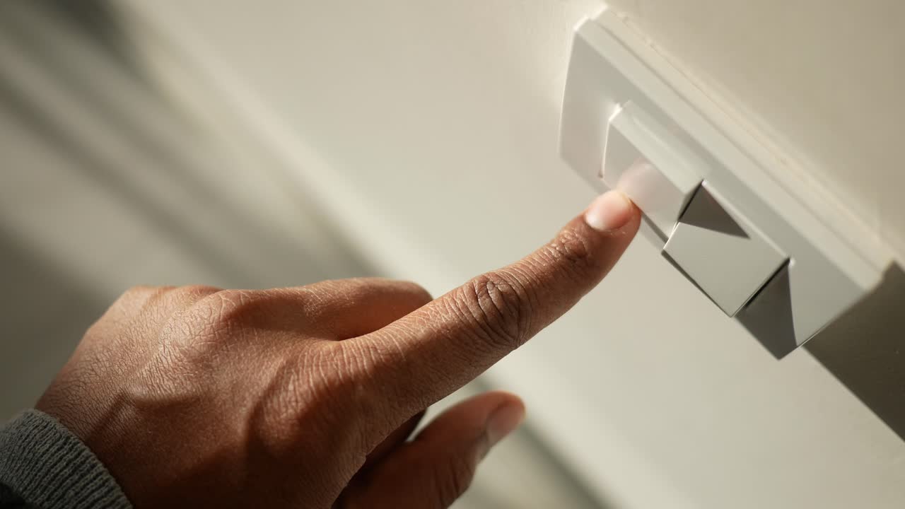 un primer plano de una mano encendiendo un interruptor de luz
