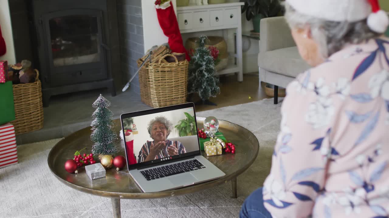mujer mayor caucásica usando una computadora portátil para una videollamada de navidad con una mujer sonriente en la pantalla