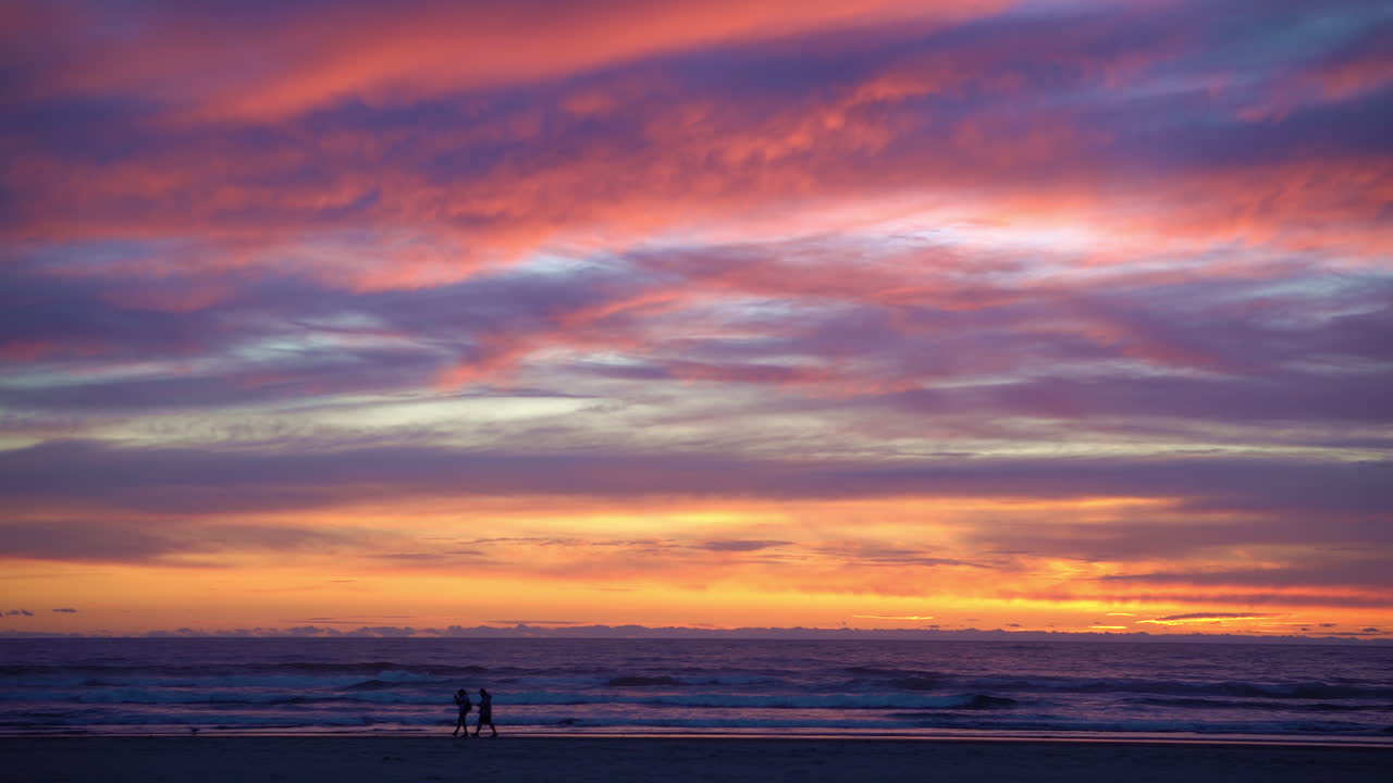 People watching a brilliant sunset in Cannon Beach Oregon from the beach.