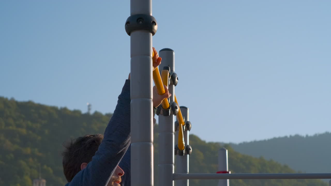 야외 체육관 장비 에서 풀업 을 하는 남자