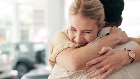 couple hugging at car dealership after buying new car