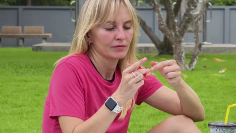 mujer sentada en un parque sosteniendo un pequeño objeto
