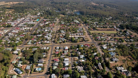 Aerial-top-view-of-city-with-bordering-lake-and-rainforest-during-wet-dry-summer-day-in-Australia