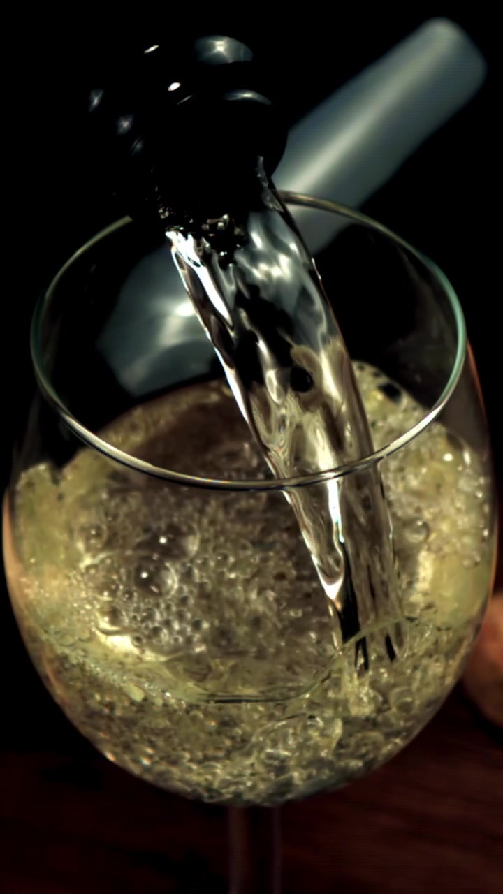 Primo piano di vino bianco versato in un bicchiere con bollicine