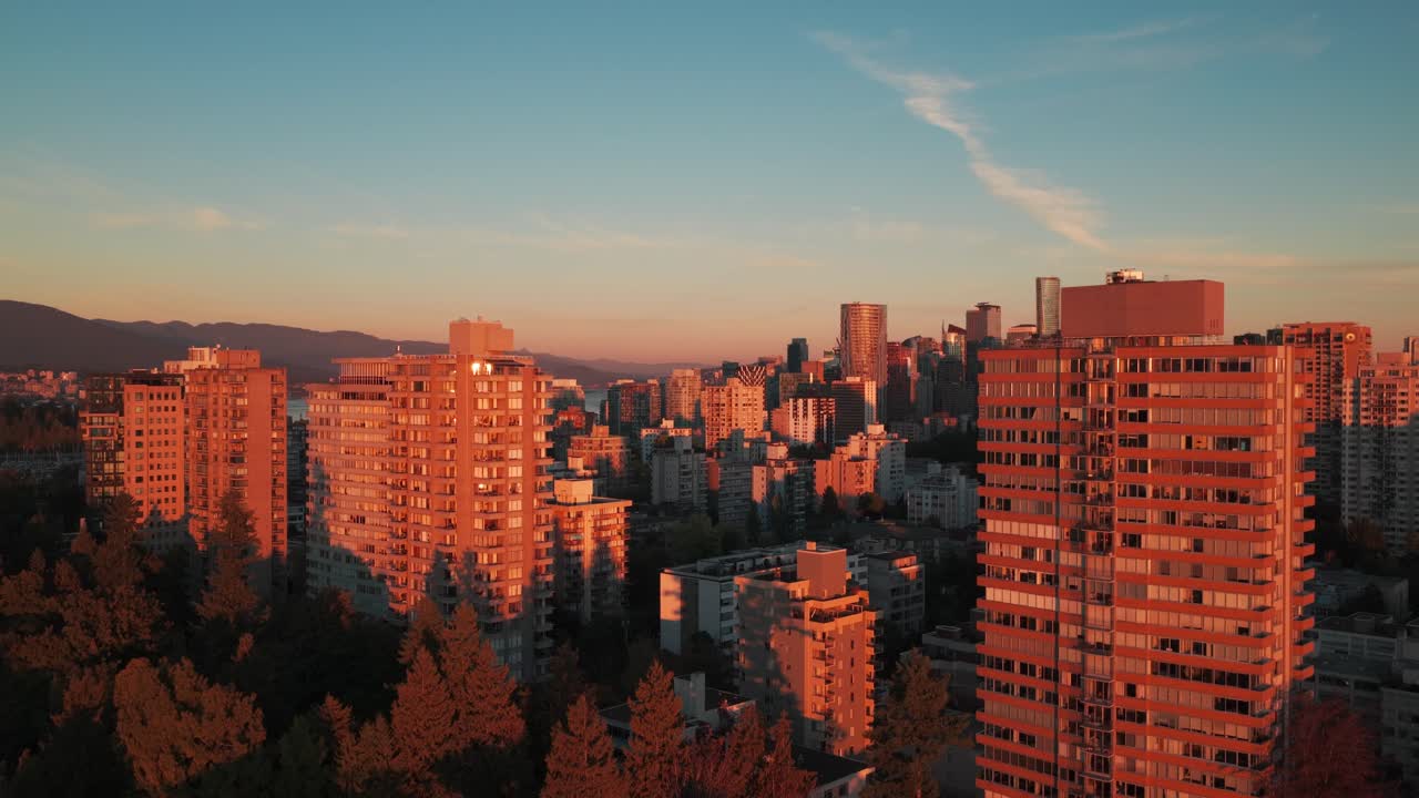 Low rising aerial shot of skyscrapers adjacent to Stanley Park at sunset in downtown Vancouver, British Columbia, Canada. 4K
