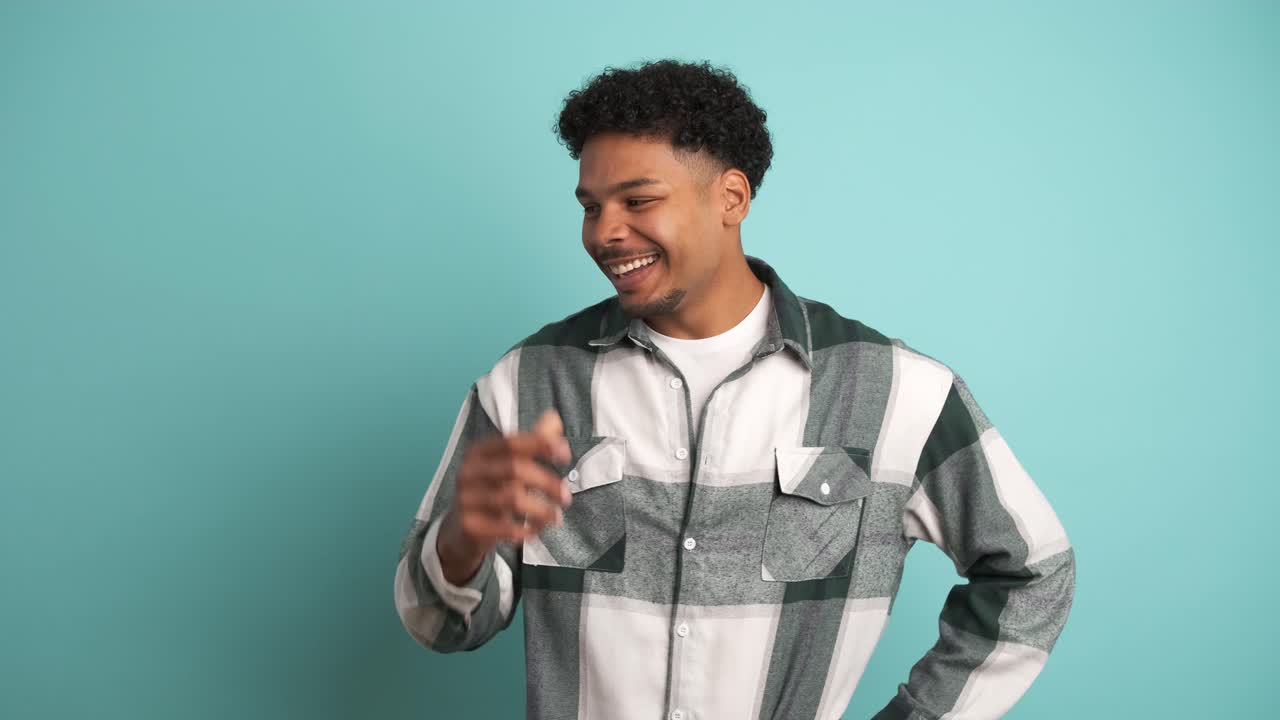 Happy young man in shirt laughing in blue studio