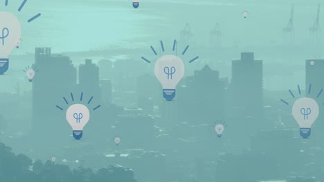 Animation-of-multiple-electric-bulb-icons-floating-against-aerial-view-of-cityscape