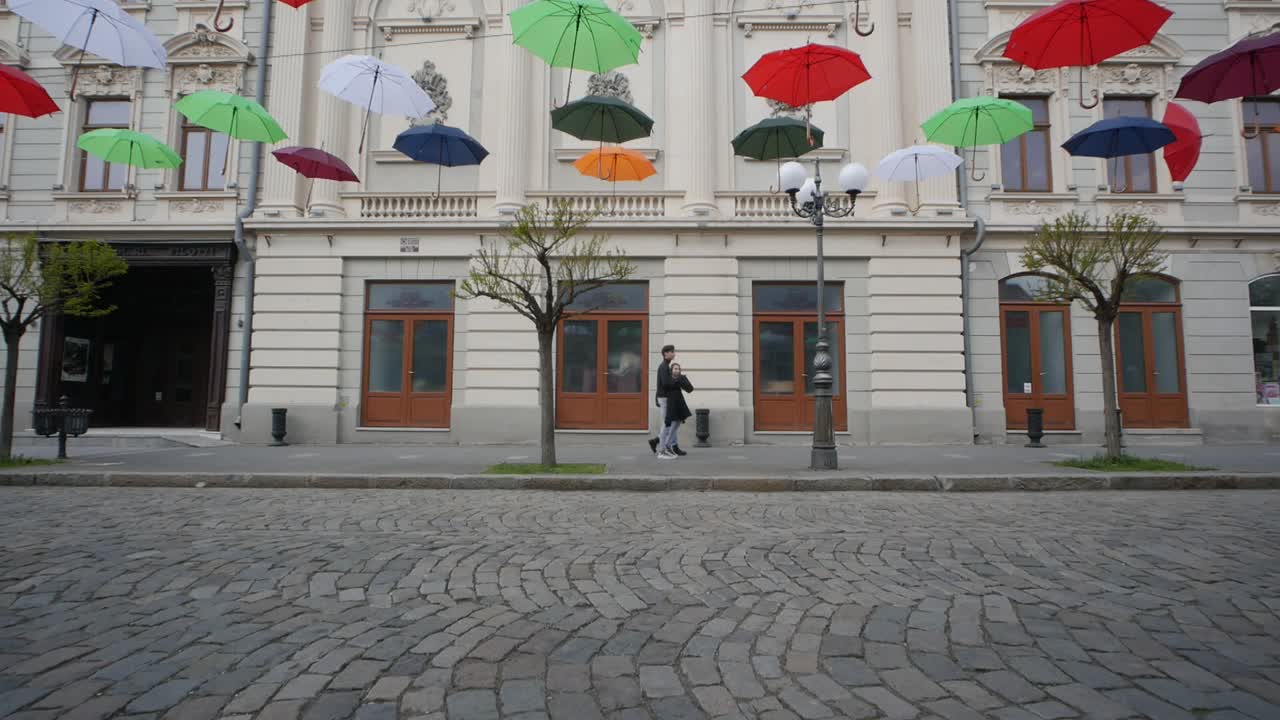 Braila, Romania. April 24 2019 The old central part. Cobbled street. Ancient architecture and multicolored umbrellas hanging in the air. Artistic atmosphere.