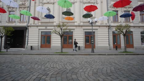 braila, romania. april 24 2019 the old central part. cobbled street. ancient architecture and multicolored umbrellas hanging in the air. artistic atmosphere.