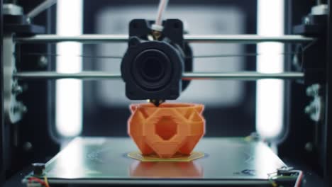 a close-up view of a 3d printer in action, creating a detailed orange object layer by layer in a technology-driven environment, showcasing modern manufacturing techniques
