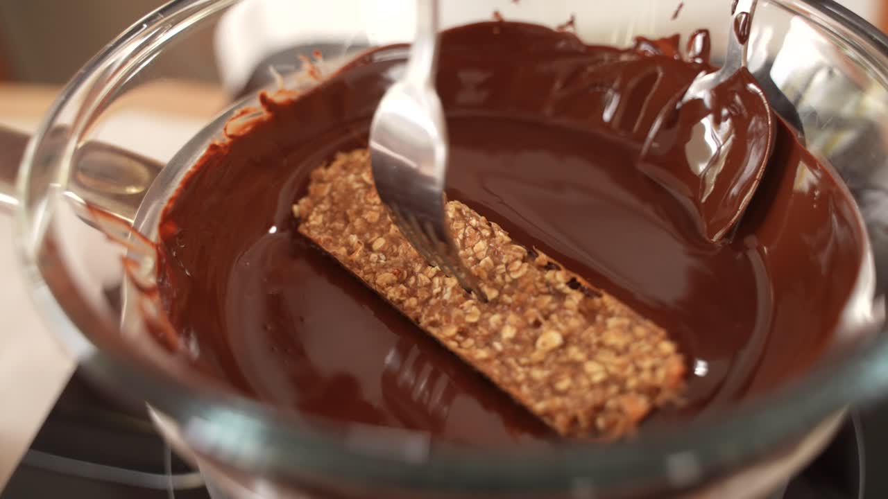 Barretta di avena salutare fatta in casa intinta nel cioccolato fuso, primo piano
