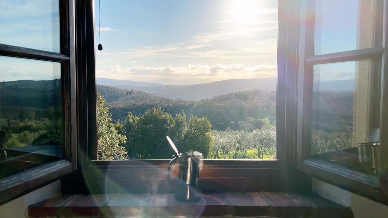 Hot coffee maker on a window sill in the morning with hills in the background