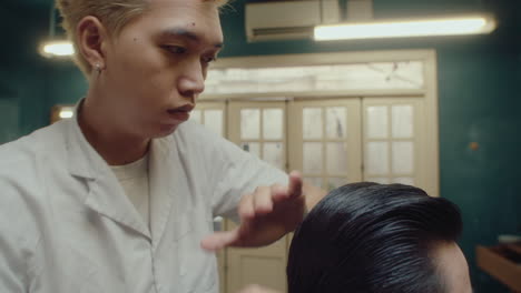 asian barber using comb and styling client hair
