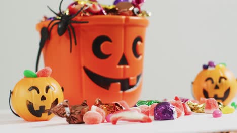 scary halloween pumpkin printed bucket full of candies against grey background