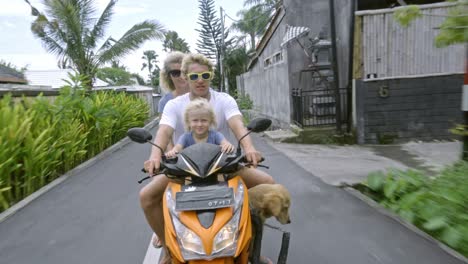 joyful family riding on scooter with dog