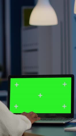 vertical video back view of black business woman looking at laptop with greenscreen