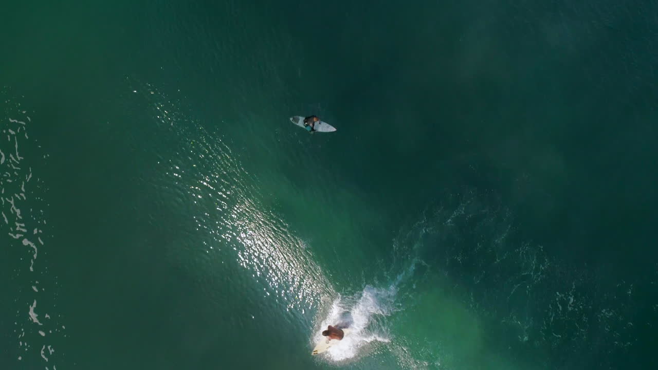Rallentatore: Ripresa aerea zenitale cinematografica di un surfista che cavalca una grande onda a tubo che crea un arcobaleno sulla spiaggia di Zicatela, Puerto Escondido, Oaxaca