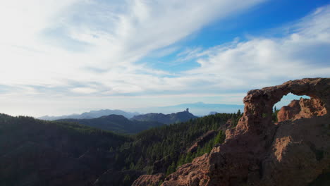 Vista-Aérea-En-órbita-Sobre-La-Ventana-De-Roque-Nublo-En-La-Isla-De-Gran-Canaria-Y-Revelando-El-Volcán-Teide.