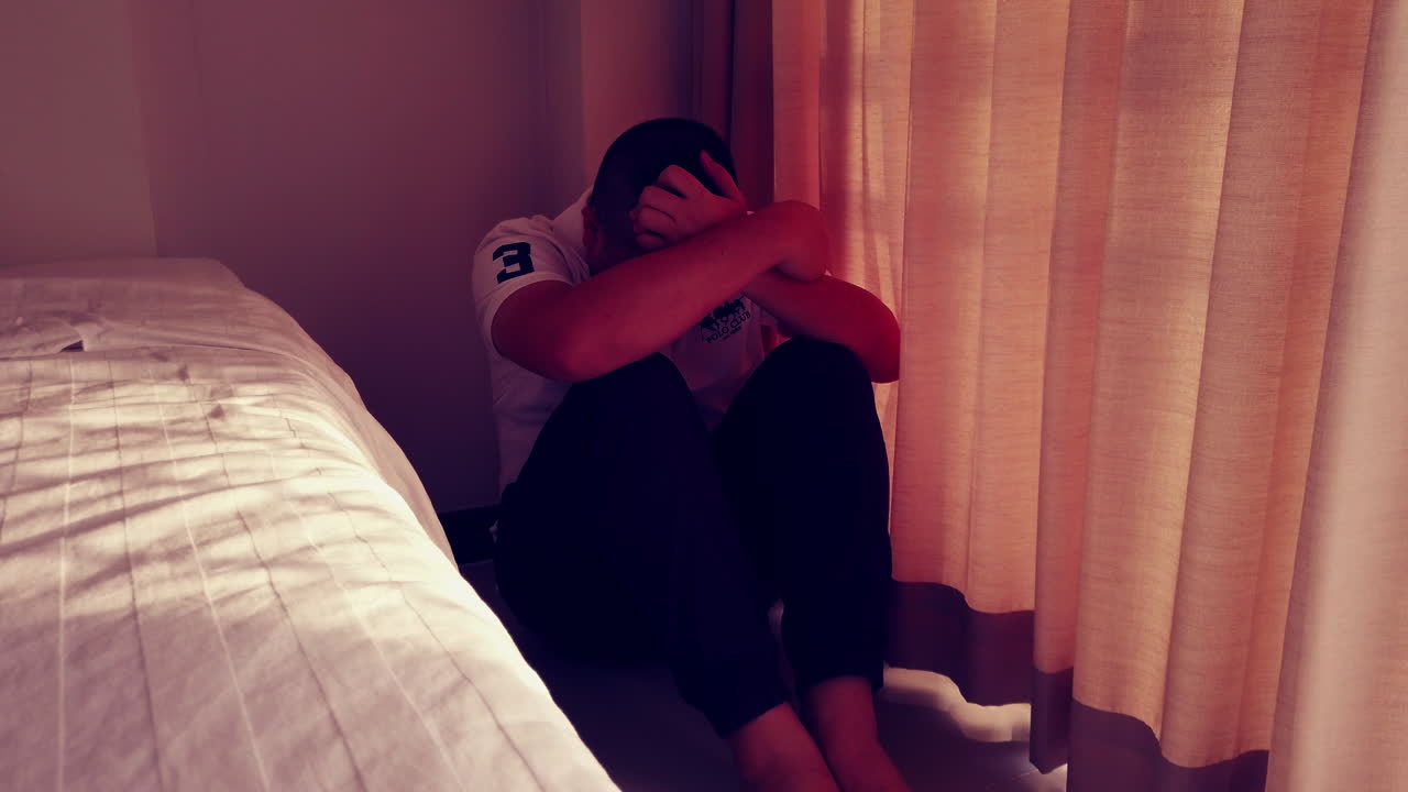 슬픈 남자는 그의 아파트 벽 모퉁이에 서서 손으로 얼굴을 가리고 있다