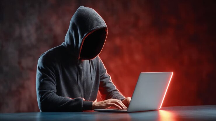 En mystisk skikkelse skjult i skygger er engageret i digital aktivitet, hvilket fremhæver den spændende verden af cyberintriger og anonymitet i den moderne tidsalder